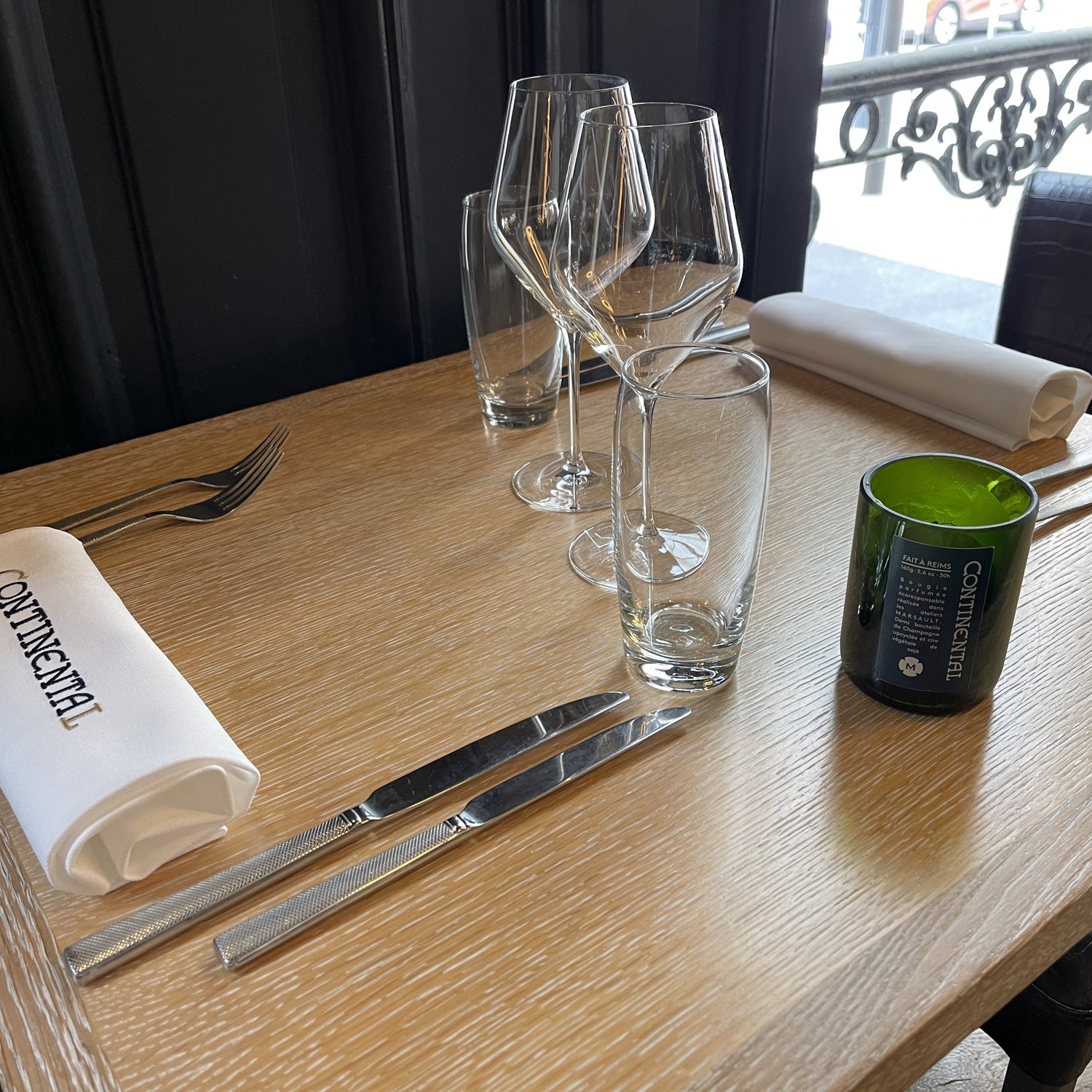Bougie format demie bouteille posée sur une table en bois de l'hotel-restaurant Le Continental situé à Reims 
