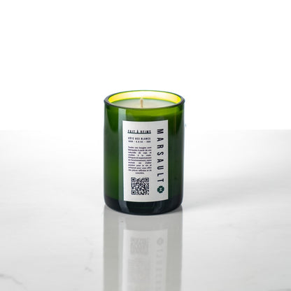 bougie Marsault verte format demi-bouteille avec mèche en coton posée dans un studio photo blanc 